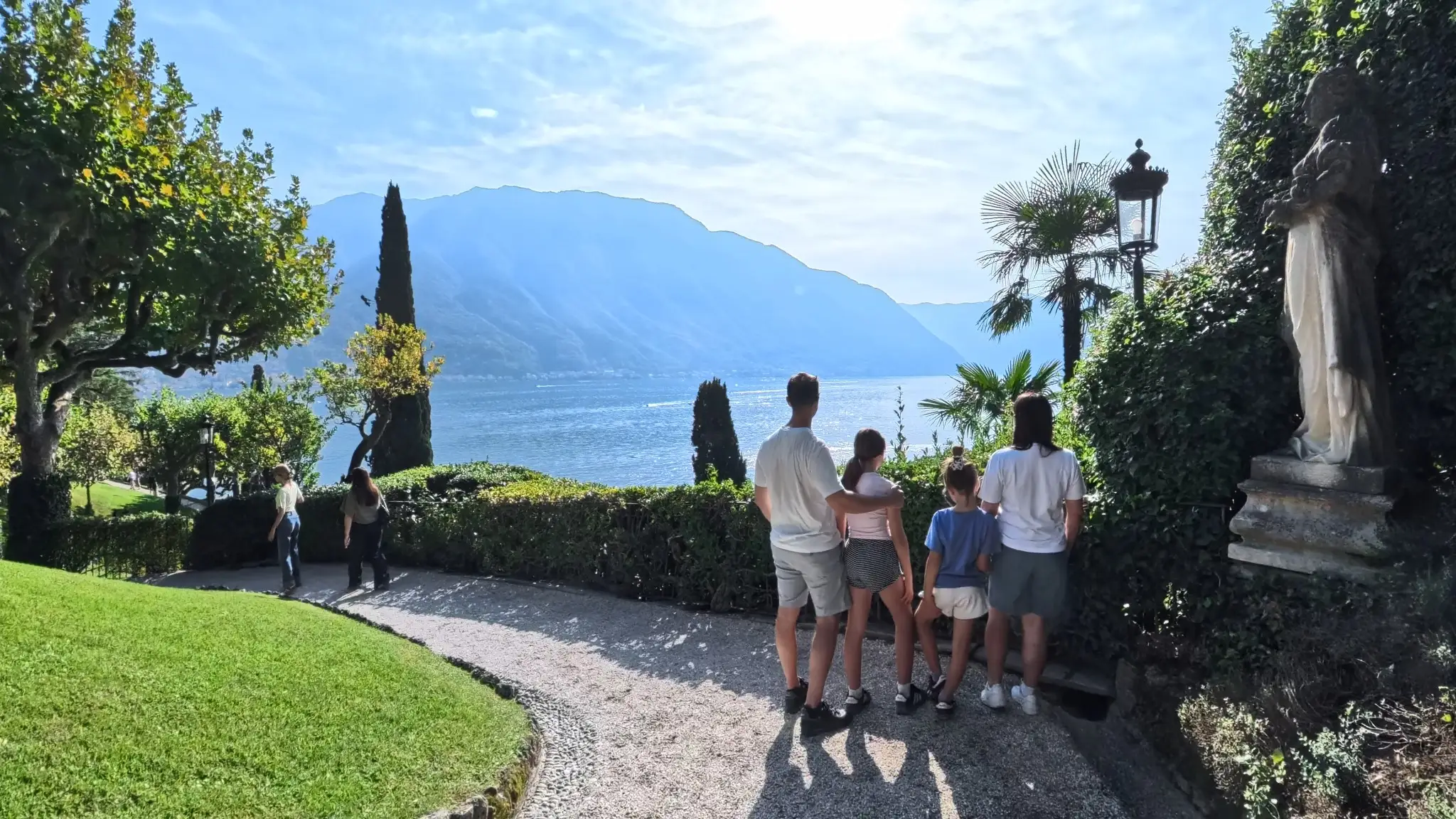 Rodzina na ścieżce w ogrodach Villa del Balbianello z widokiem na jezioro